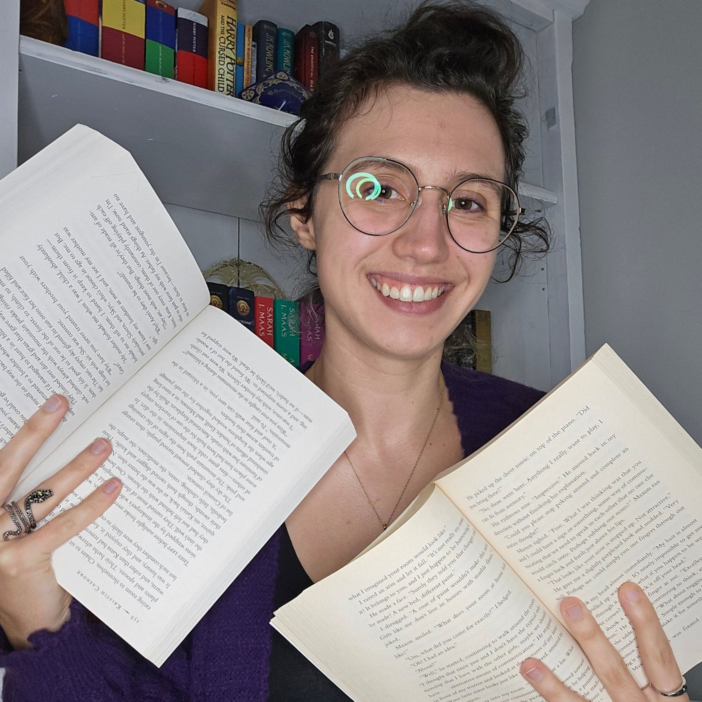 Person holding two open books with a bookshelf in the background