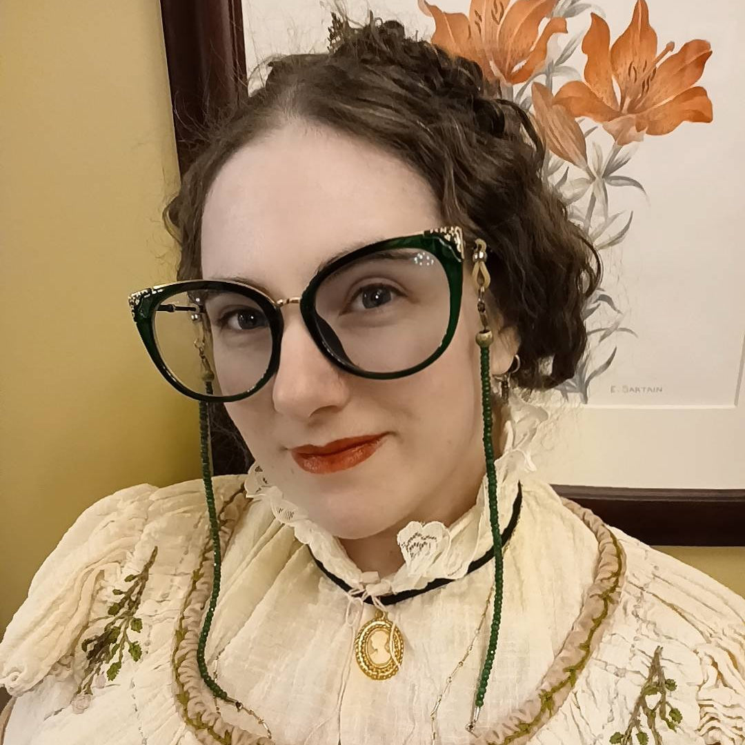 Astra Crompton wearing a white embroidered dress with a floral background