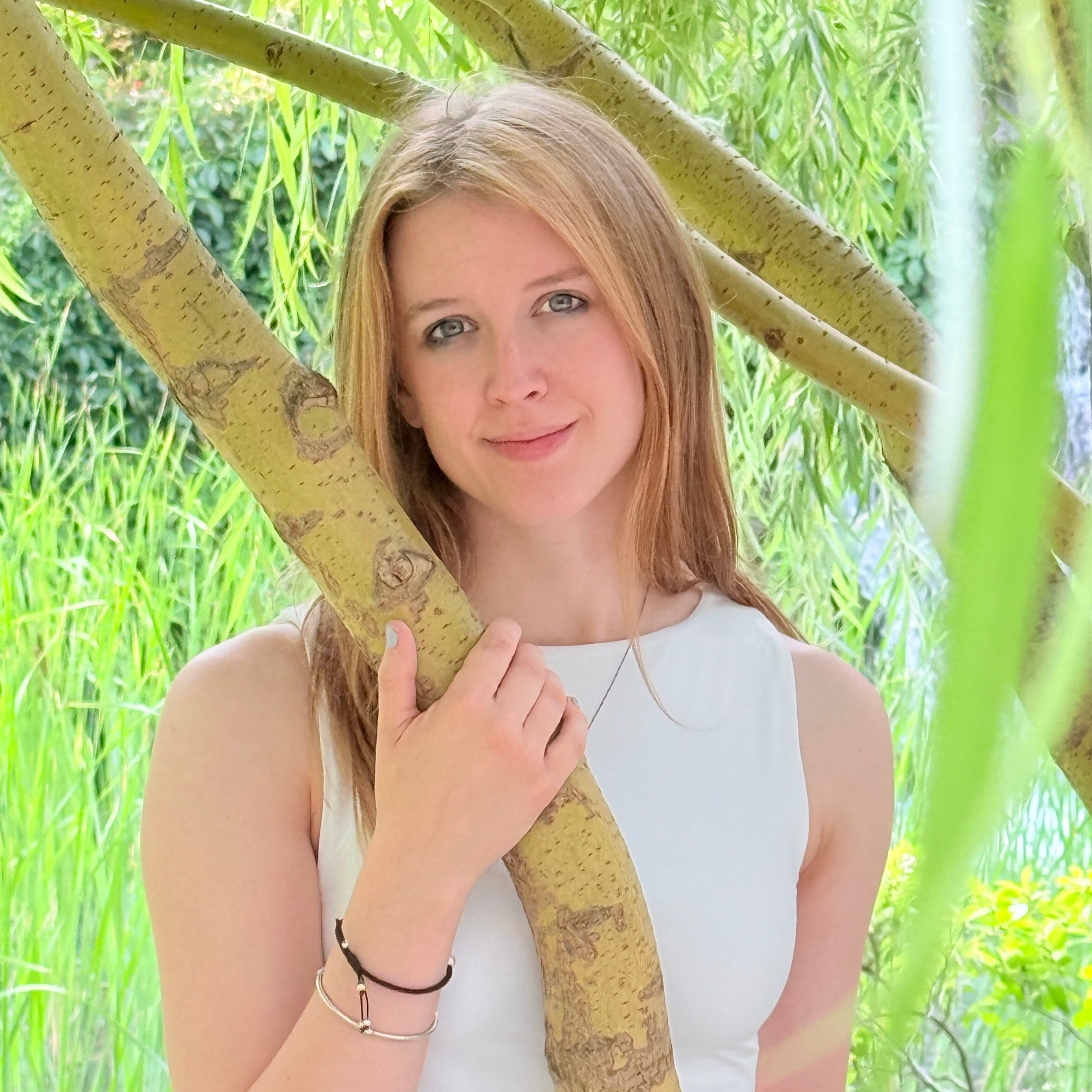 Person holding onto a large plant stem with greenery in the background